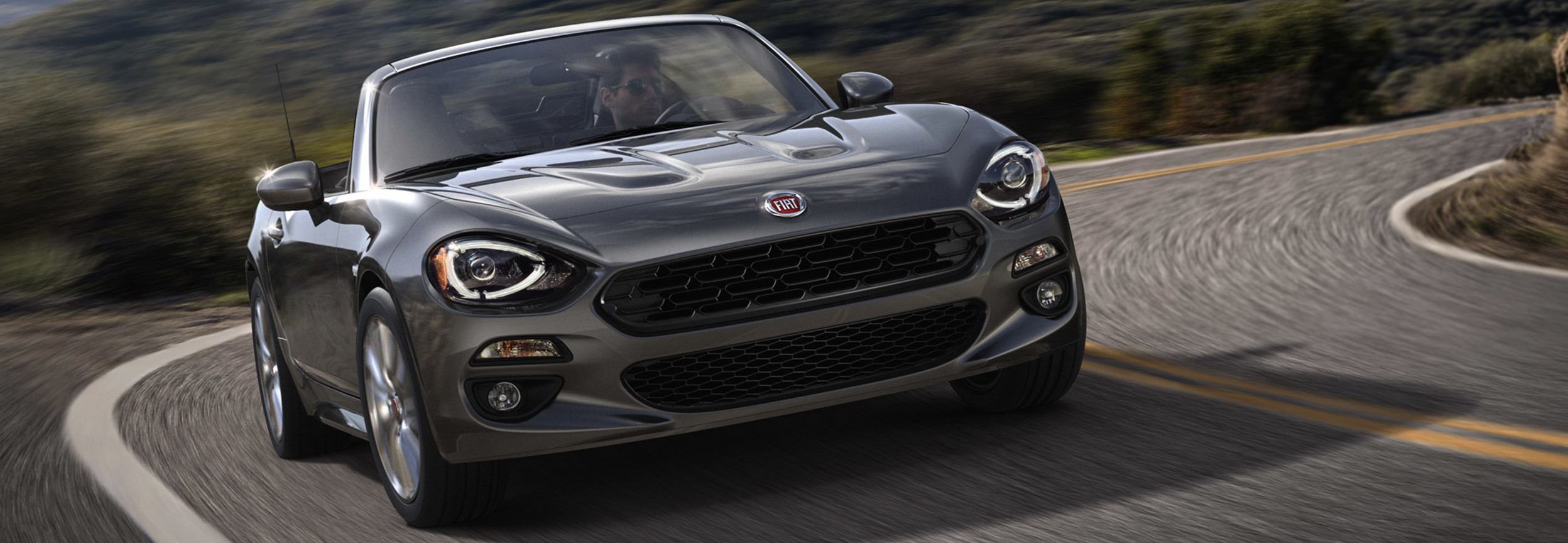 FIAT 124 Spider 2020 grise gravissant une montagne.