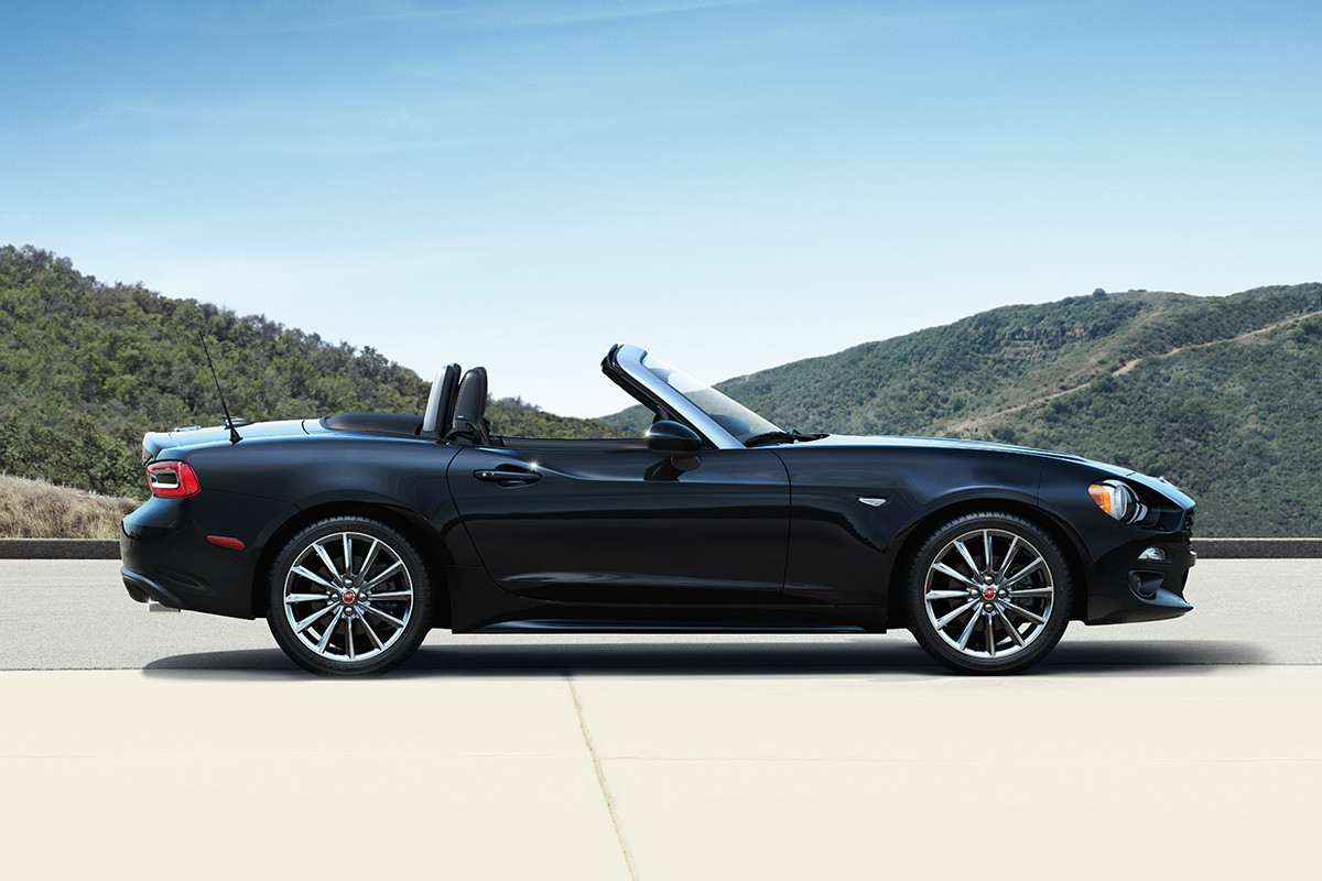 Vue latérale de la FIAT 124 Spider 2020 garée à l’extérieur, capote ouverte