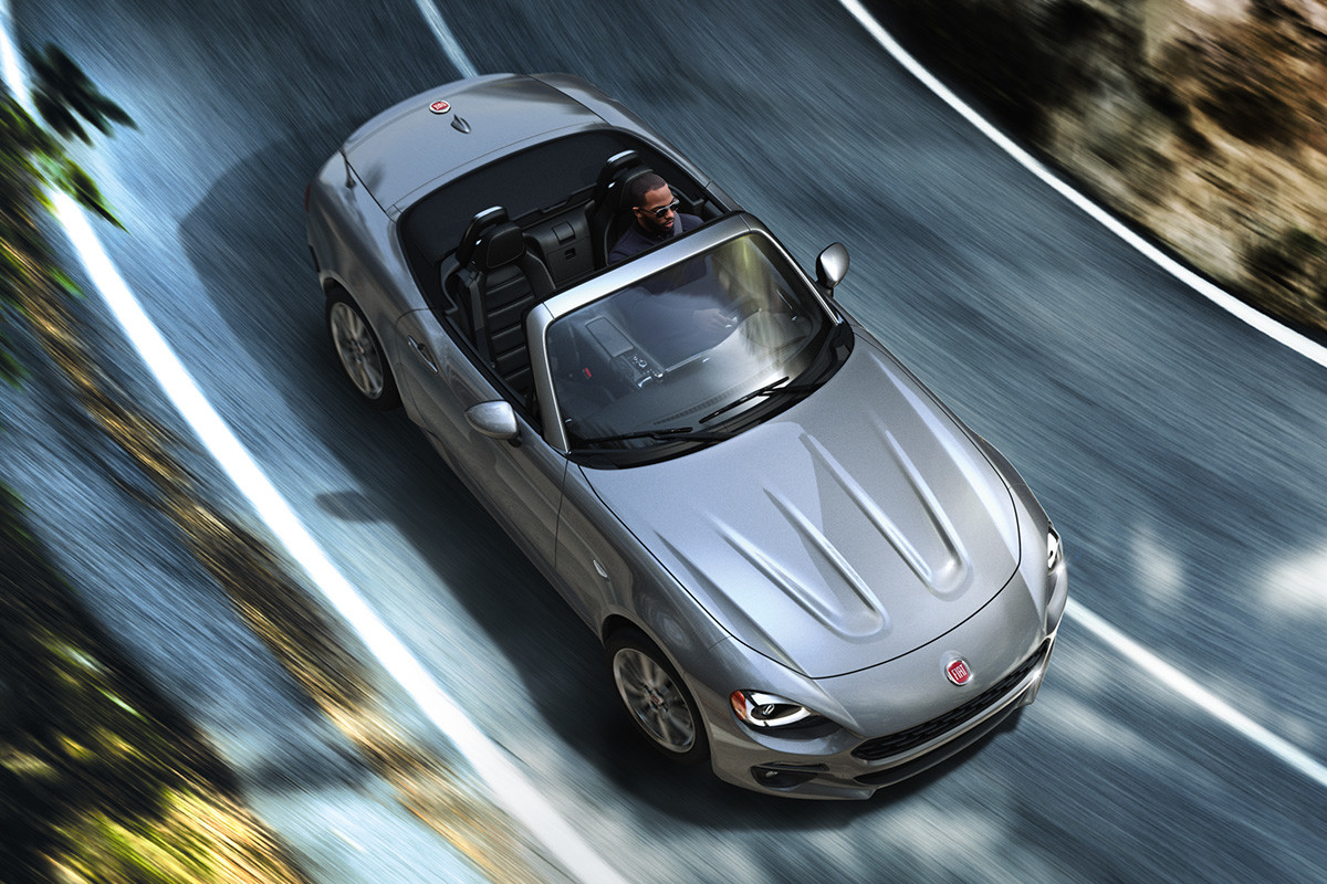 Vue aérienne de la FIAT 124 Spider 2020 roulant sur une route de campagne traversant des plaines