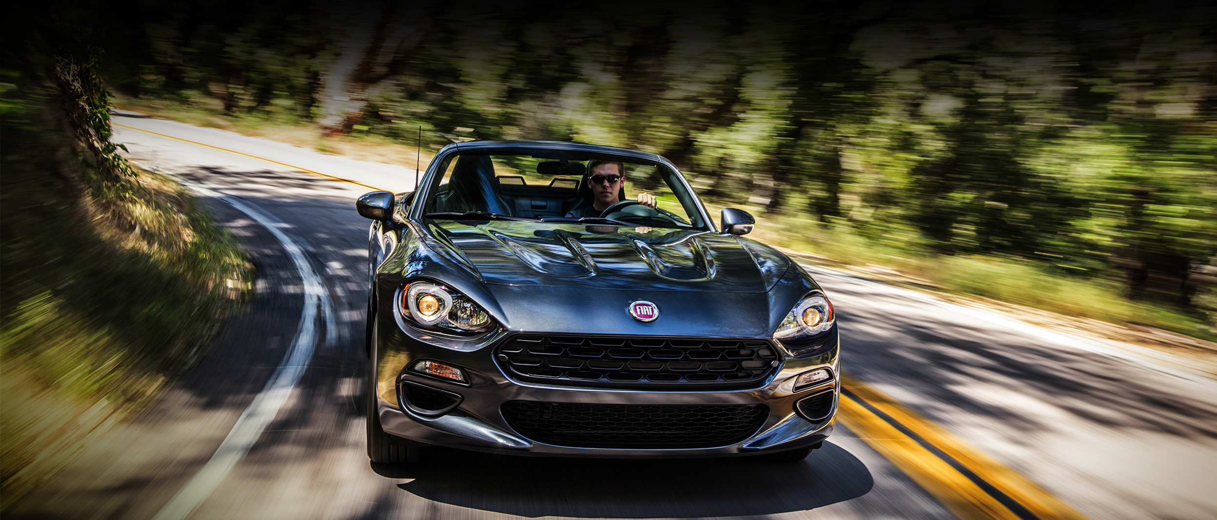 White 2020 FIAT 124 Spider being driven on a country road in a sunset
