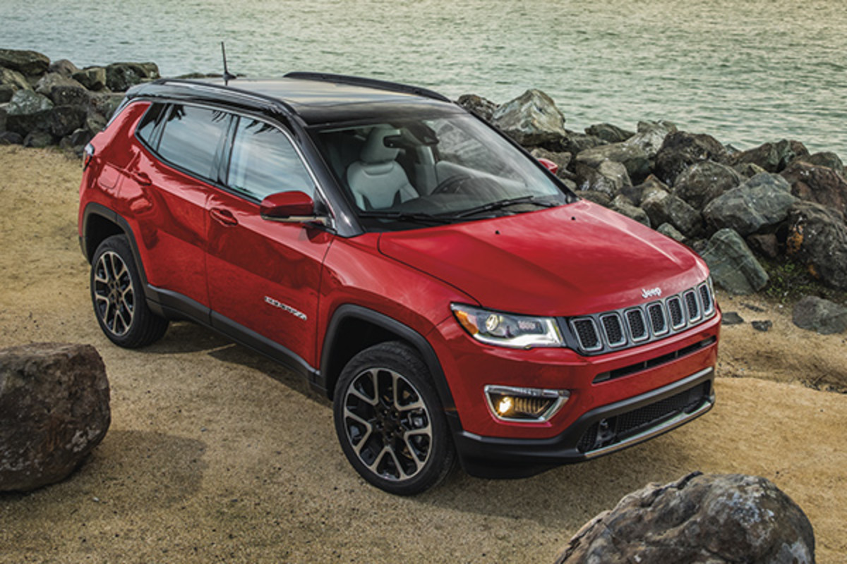 A red Jeep Compass, parked on a rocky beach.