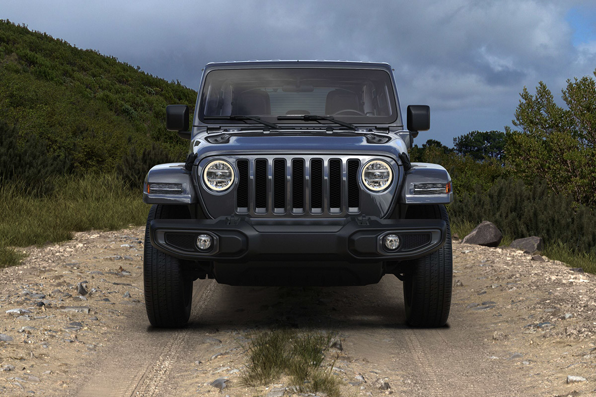Vue de face d’un Jeep Wrangler 4xe 2021 garé sur une route rocailleuse devant des montagnes.