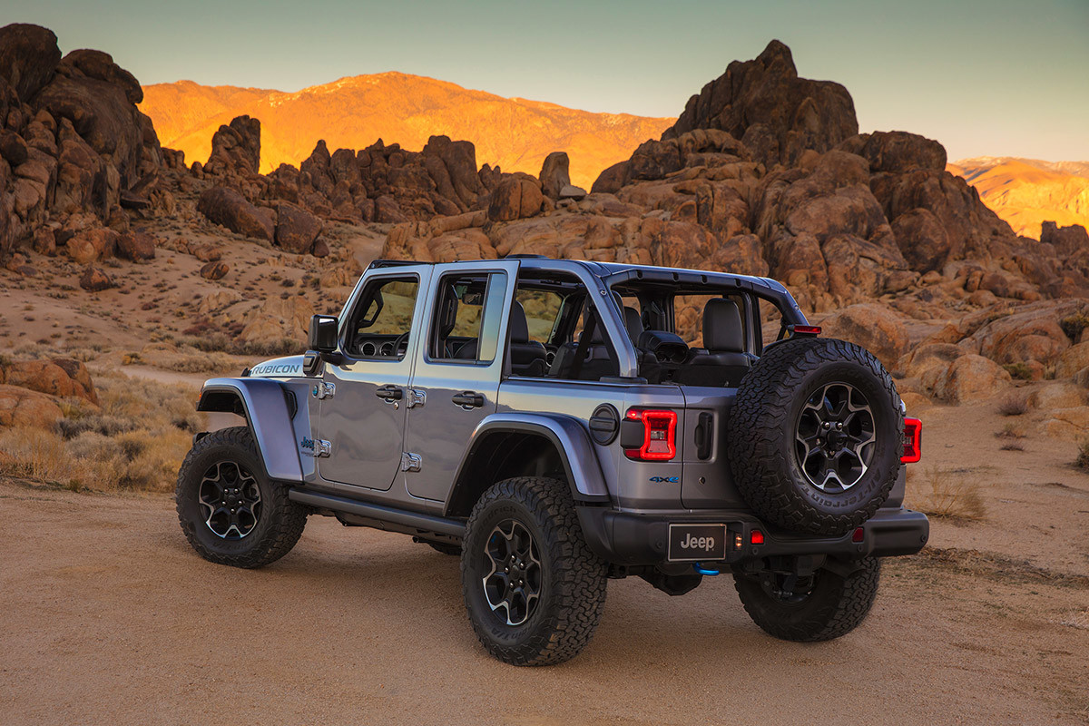 Rear view of a grey Jeep Wrangler 4xe, parked on a dirt road in a desert.
