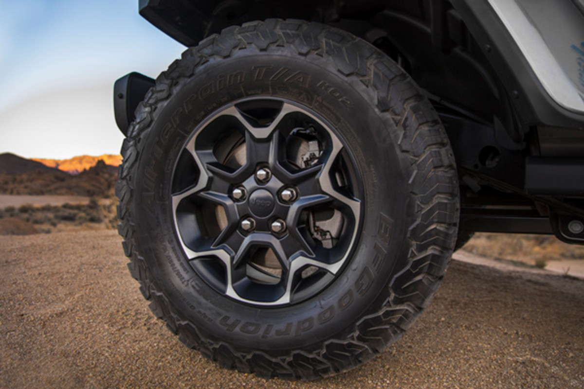 Gros plan de la roue avant gauche du Jeep Wrangler 4xe 2021 sur un chemin de terre.