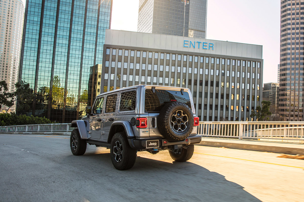 Vue arrière d'un Jeep Wrangler 4xe gris sur une route.