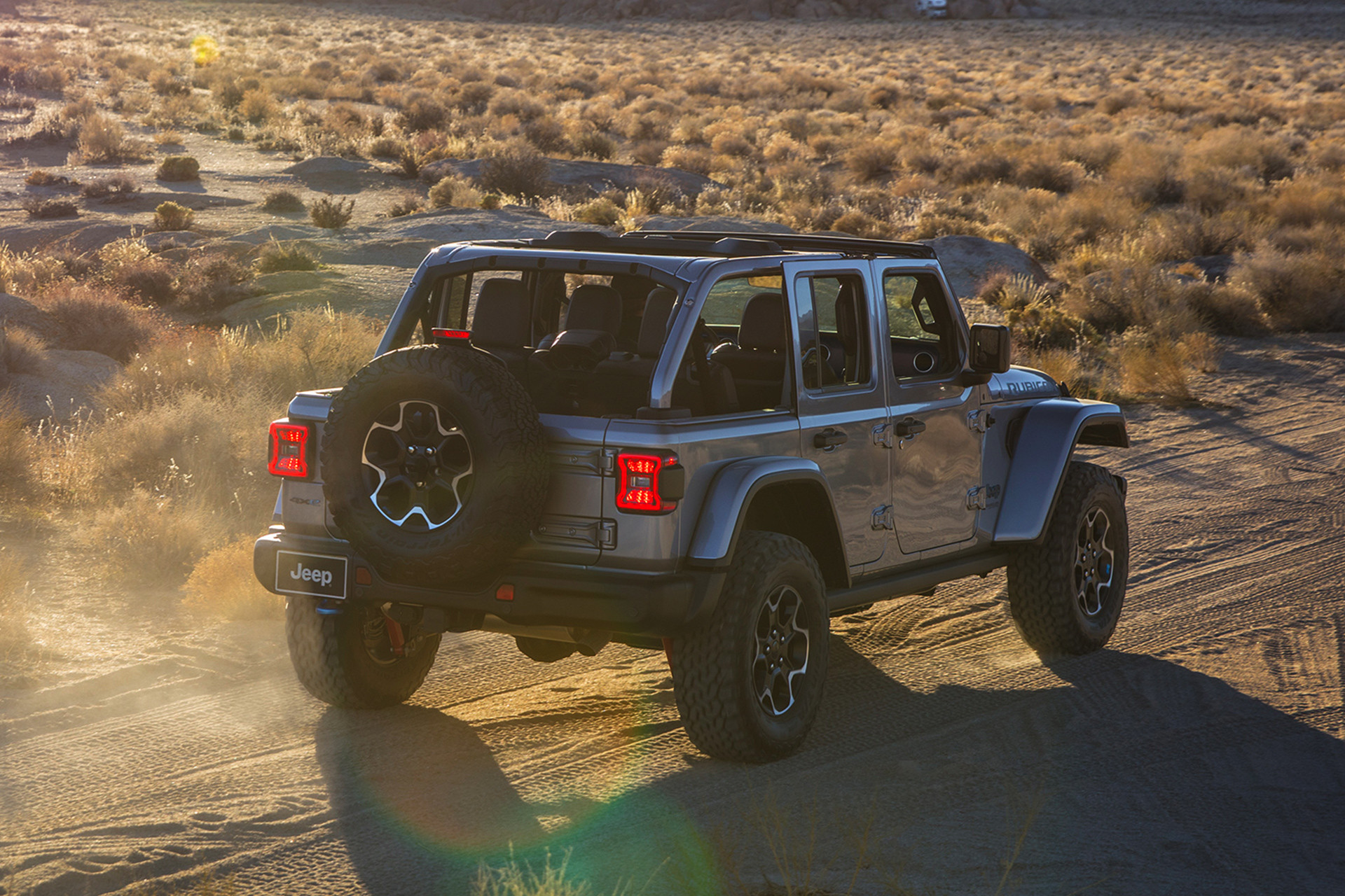 Un Jeep Wrangler 4xe 2021 roulant sur une route de terre vers les montagnes.