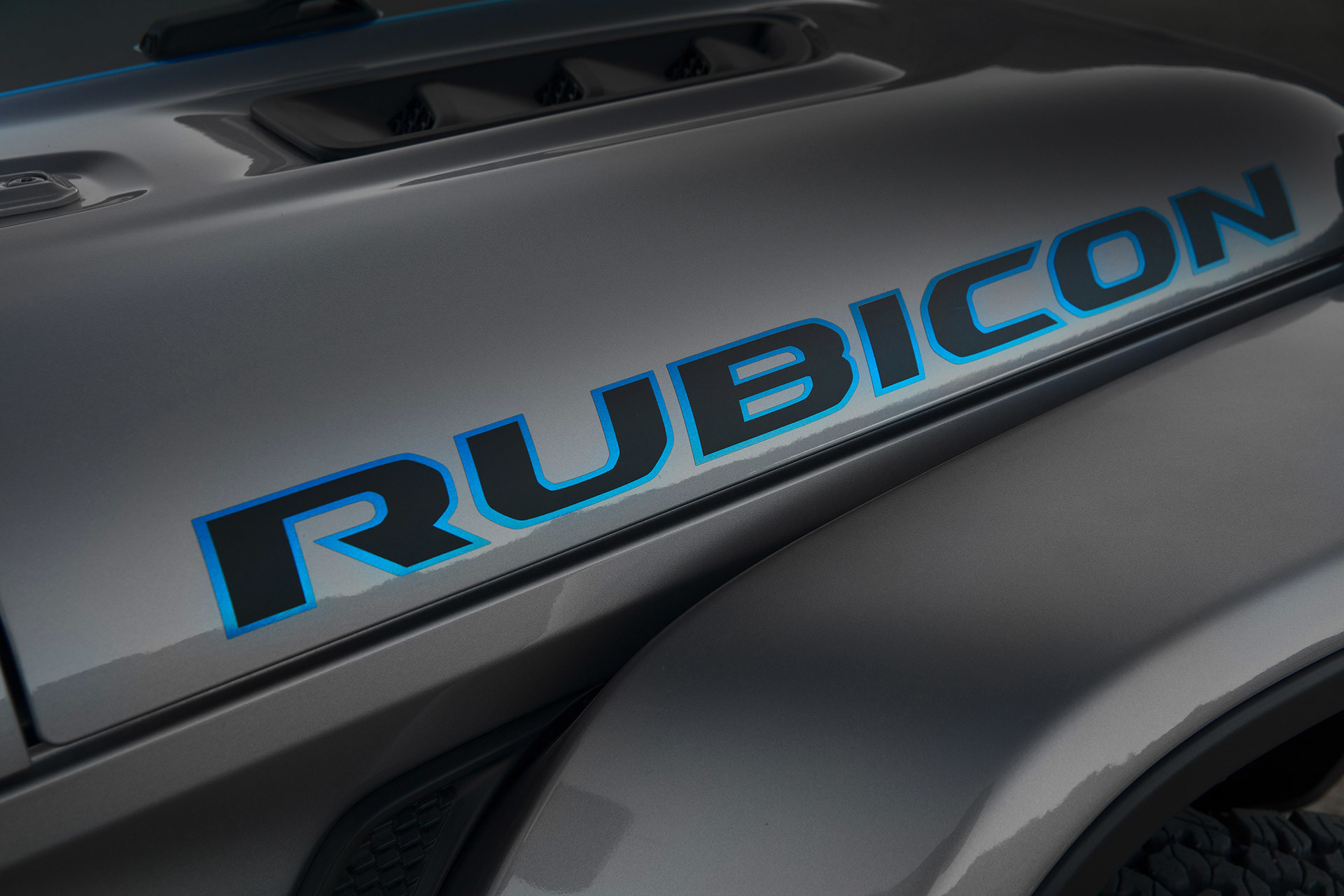 Gros plan du logo Rubicon sur un Jeep Wrangler 4xe gris.