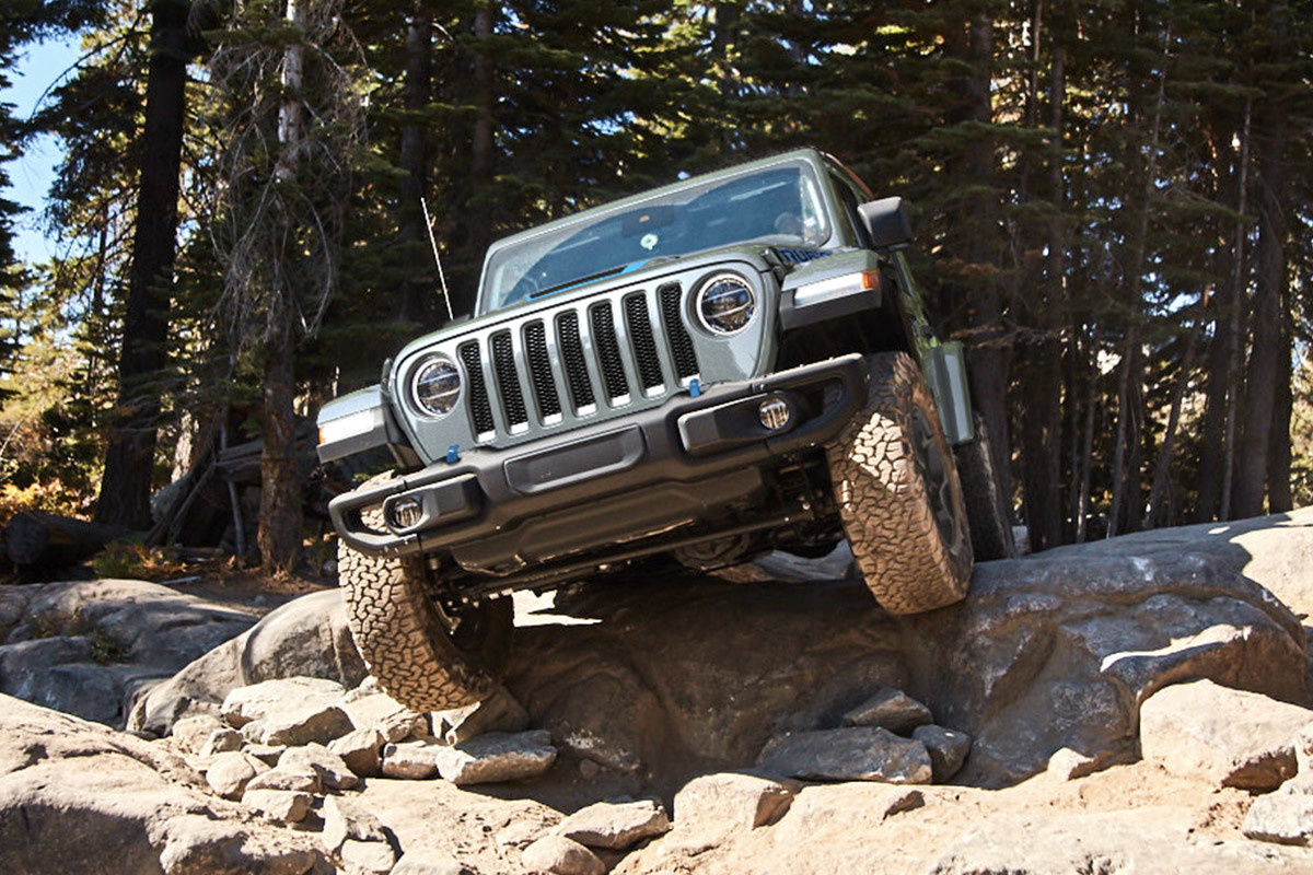 The front of a black 2022 Jeep Wrangler 4xe driving down rocky terrain.
