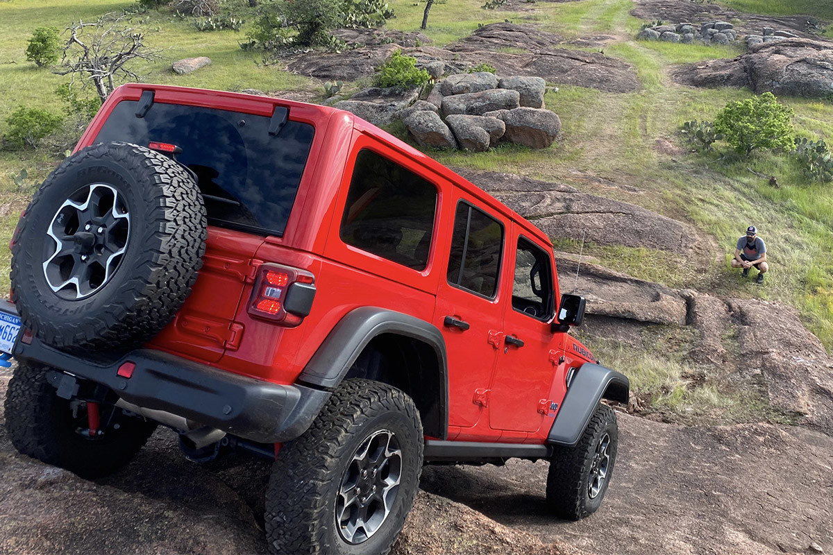 The back of a red 2022 Jeep Wrangler 4xe driving downhill.