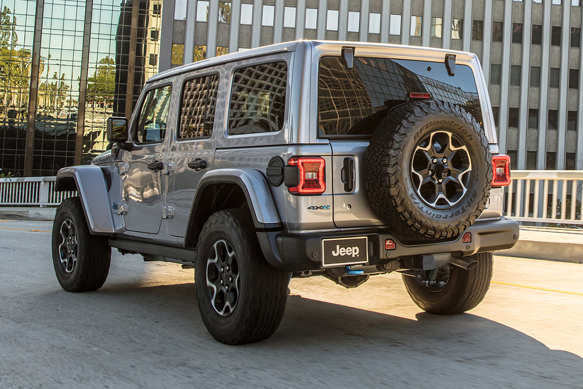 The back of a grey 2022 Jeep Wrangler 4xe driving into a city.
