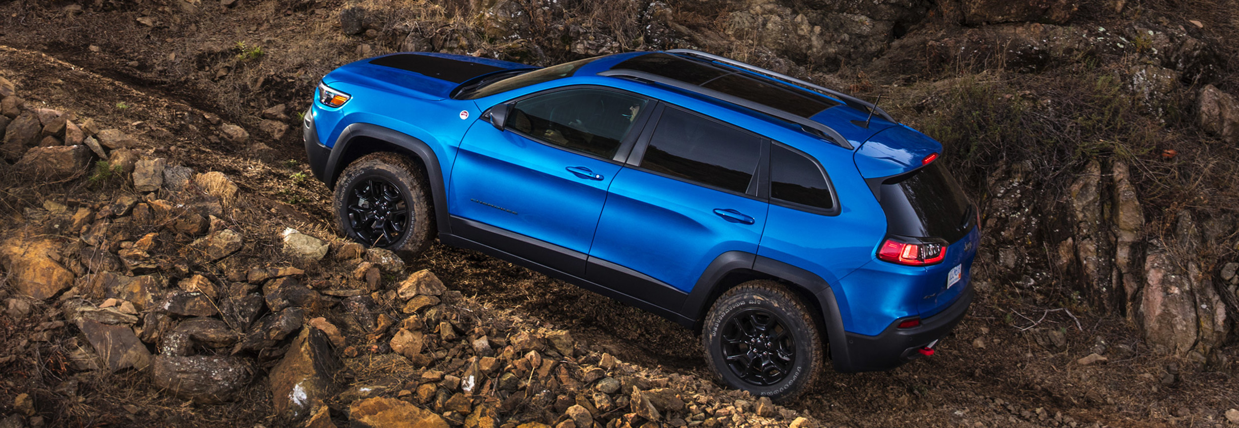 Un Jeep Cherokee bleu en train de gravir une montagne