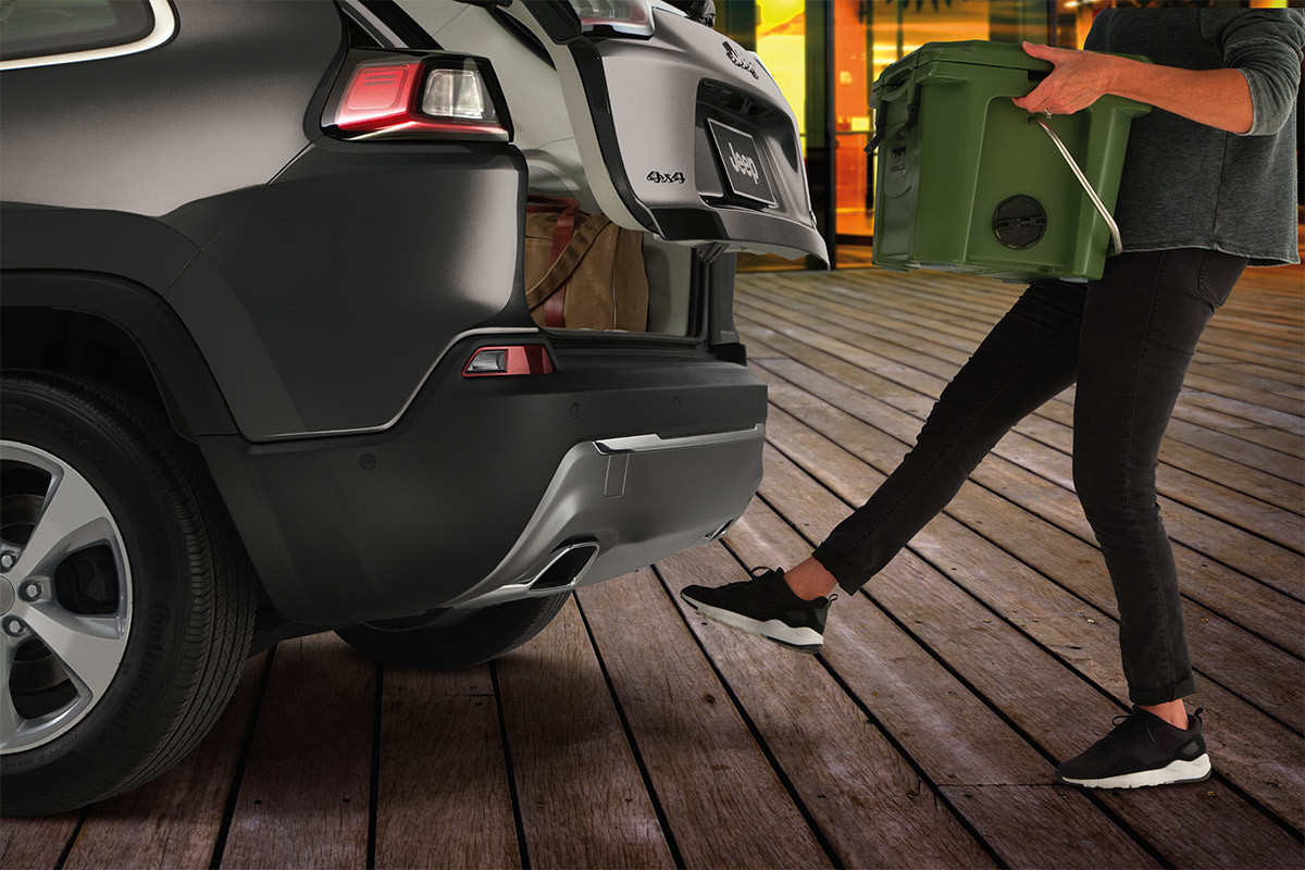 Woman kicking her foot below the rear bumper of 2020 Jeep Cherokee
