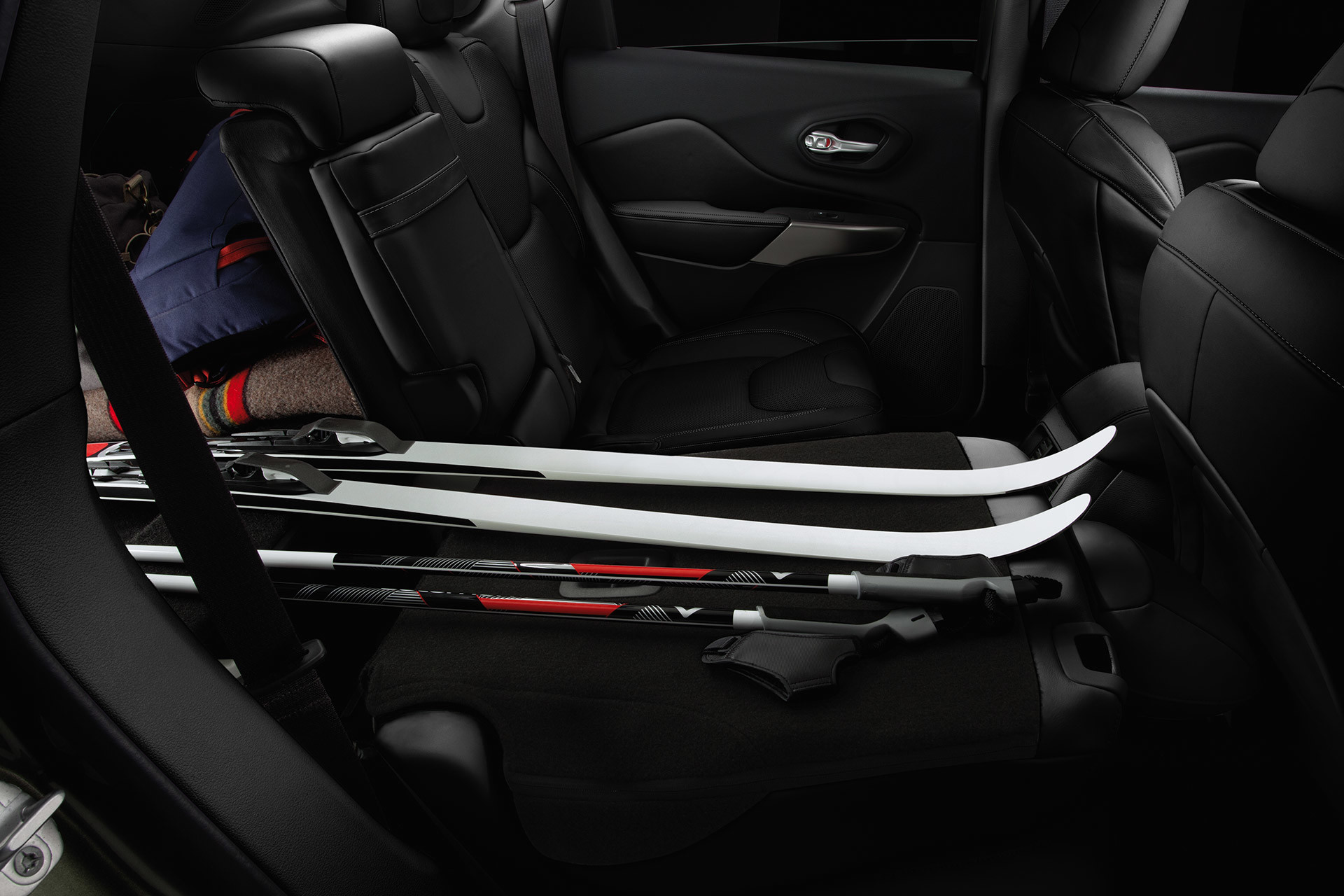 Interior of 2020 Jeep Cherokee with rear seat folded while hockey sticks are loaded