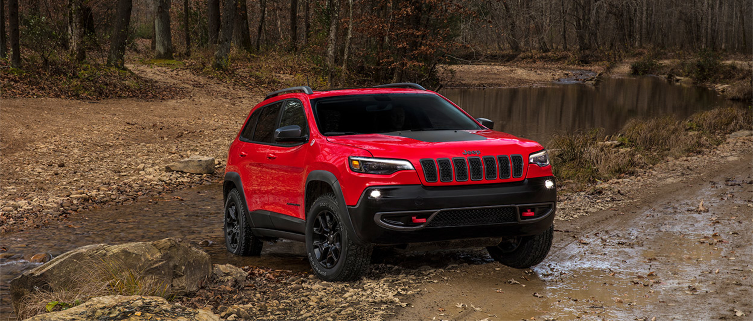 Un Jeep Grand Cherokee 2020 rouge stationné dans la forêt