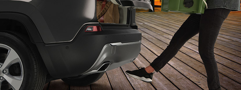 Woman kicking her foot below the rear bumper of 2020 Jeep Cherokee