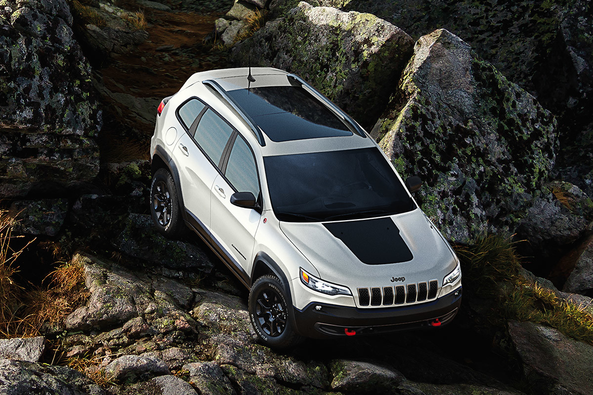 Jeep Cherokee 2021 en blanc éclatant traversant un flanc de montagne rocheux.