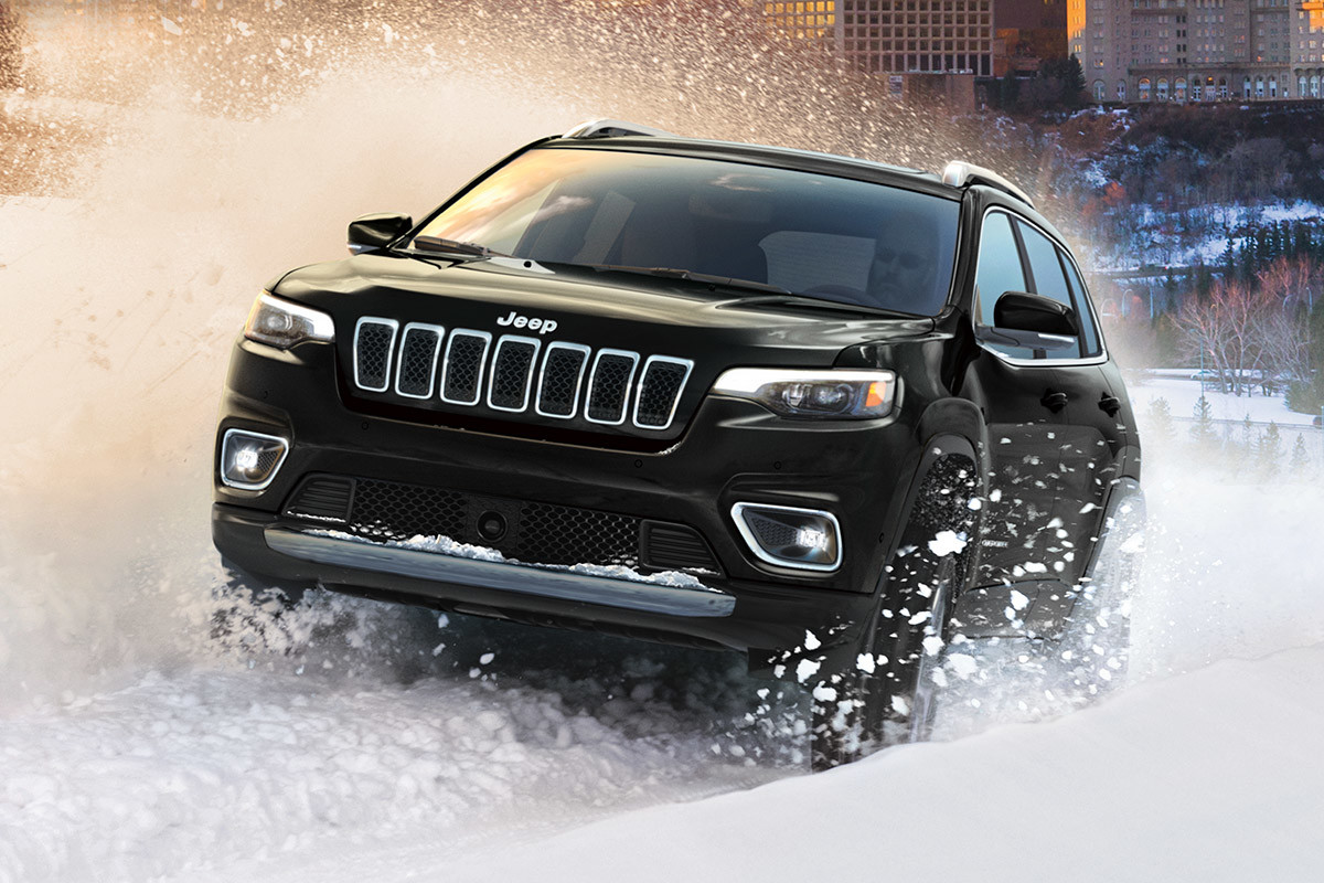 Jeep Cherokee 2021 noir roulant avec confiance dans la neige fraîche et profonde.