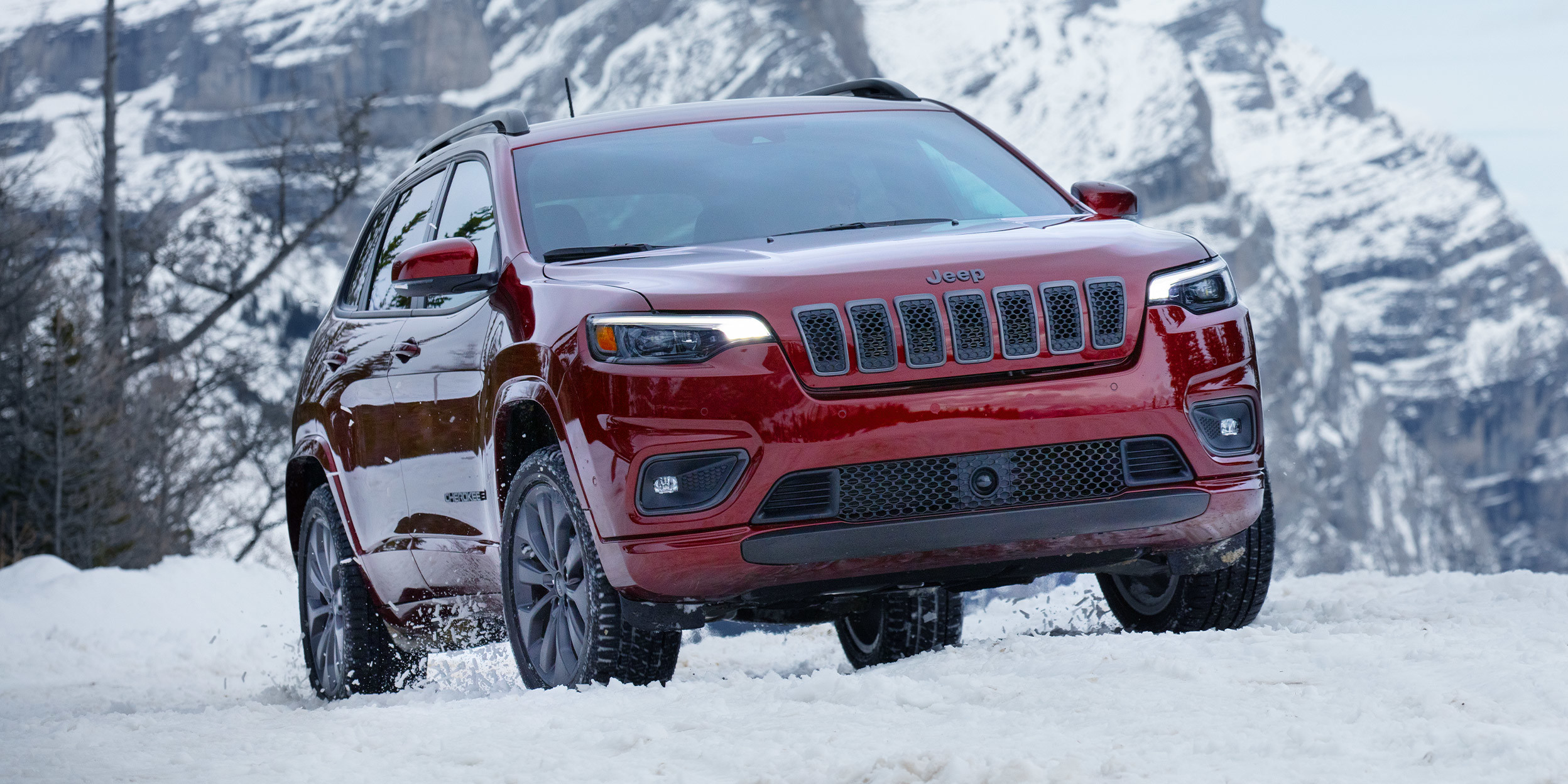 Cherokee High Altitude rouge velours roulant dans la neige avec les montagnes visibles au loin.