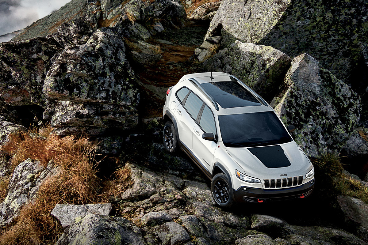 UNPARALLELED CAPABILITY 2022 Jeep Cherokee SUV climbing down a rocky off-road trail.