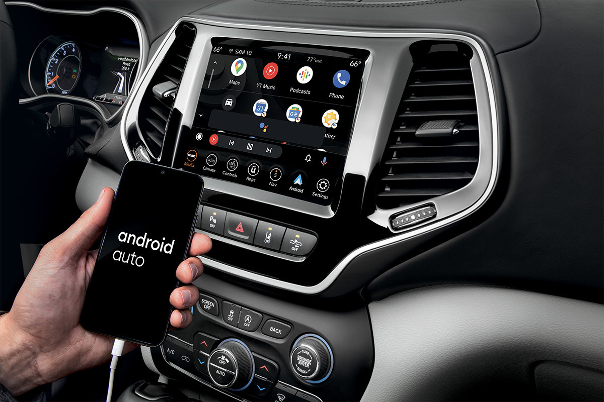 The touchscreen in the 2022 Jeep Cherokee SUV with the app screen selected and a hand held connected smartphone showing android auto.