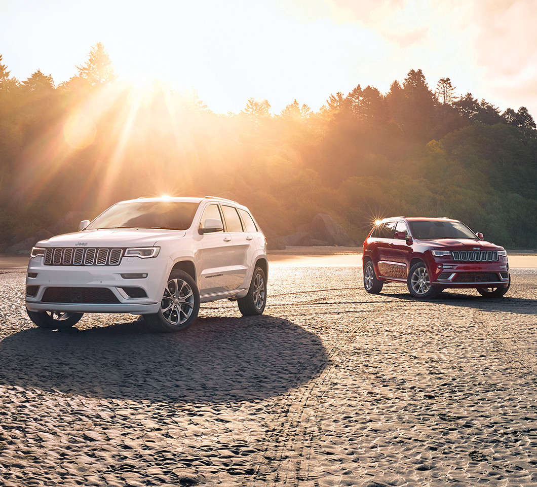 A red and white Jeep Cherokee side by side in the sunset.
