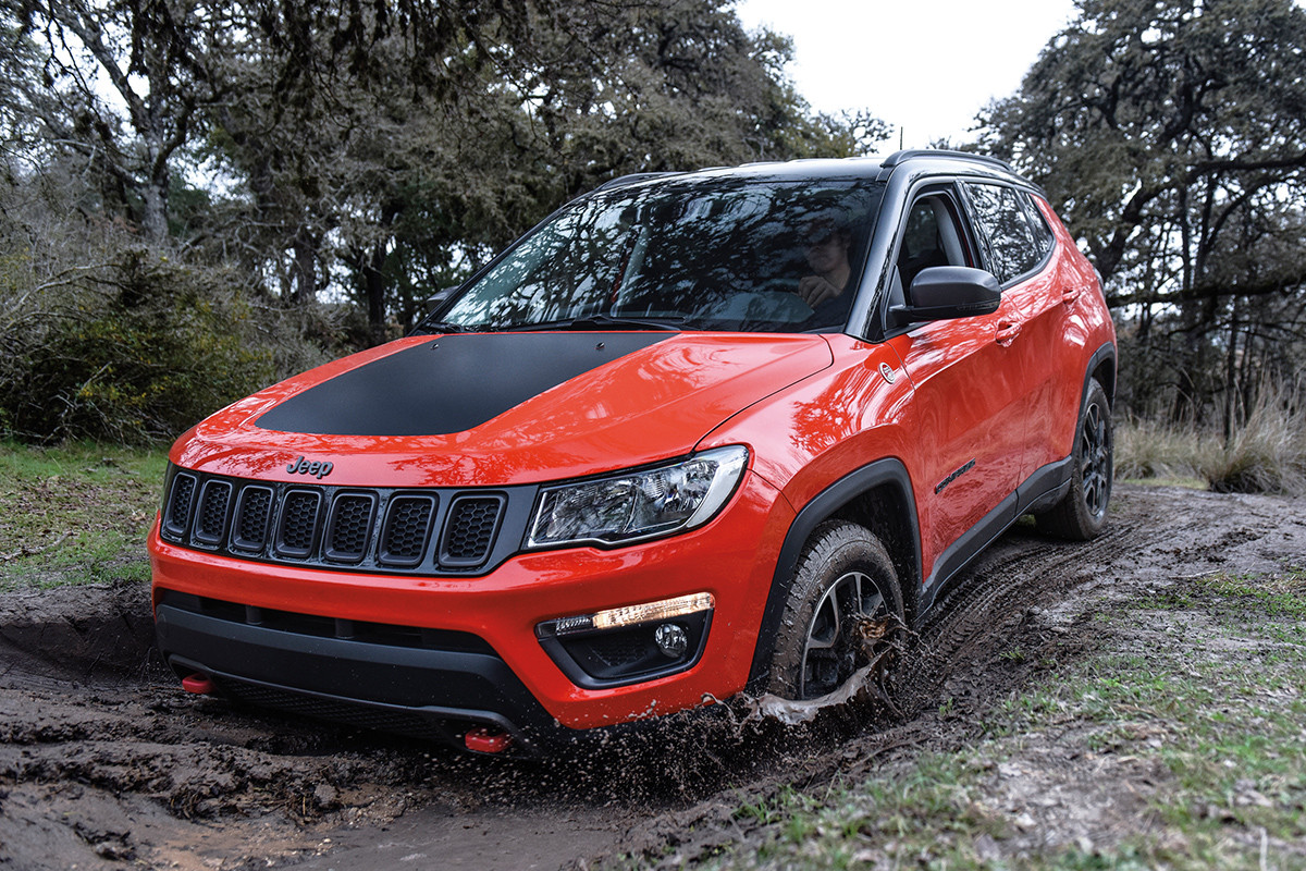 Red 2019 Jeep Compass being driven on a muddy road.