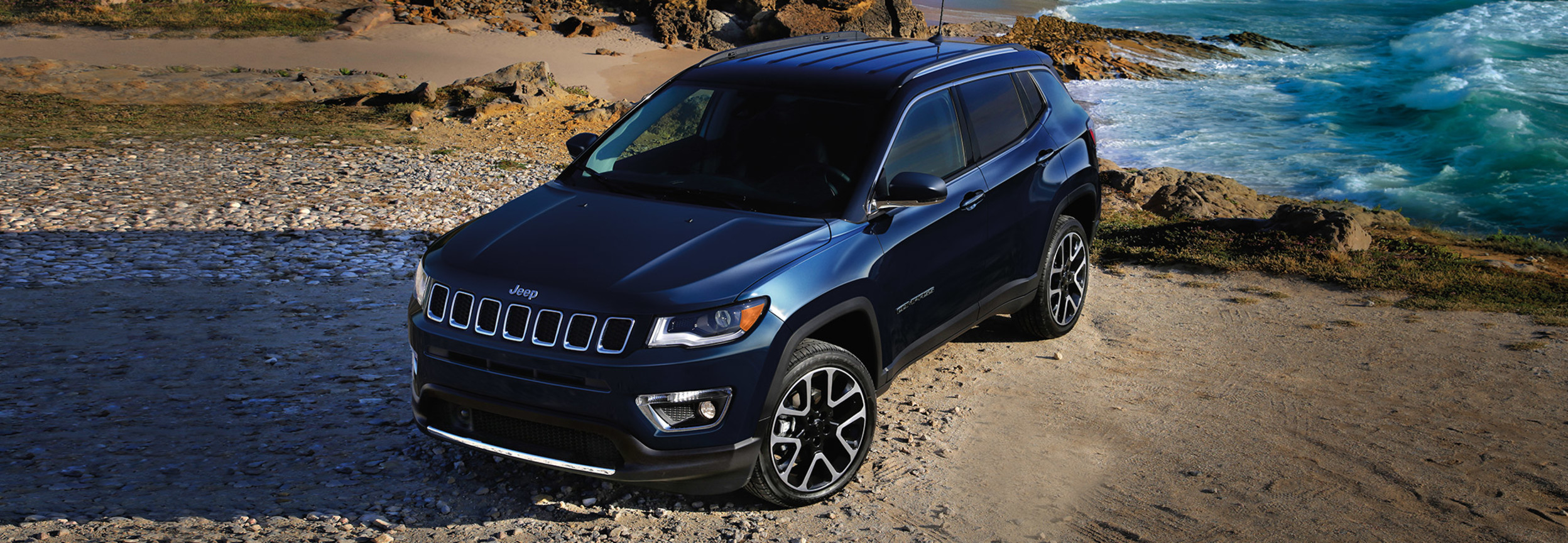 Top view of a black Jeep Compass on a cliff with the sea in the background