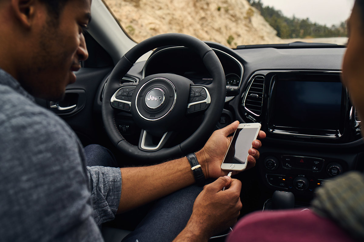 Man connecting his iPhone to their Uconnect system on a 2020 Jeep Compass.
