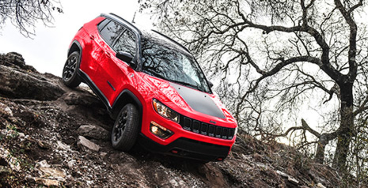 ULTRACOMPÉTENT Un Jeep Compass Trailhawk Spitfire Orange 2021 conduit sur un rocher escarpé.
