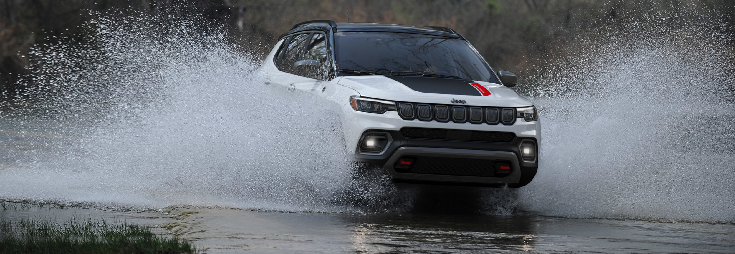 A white 2022 Jeep Compass driving through water