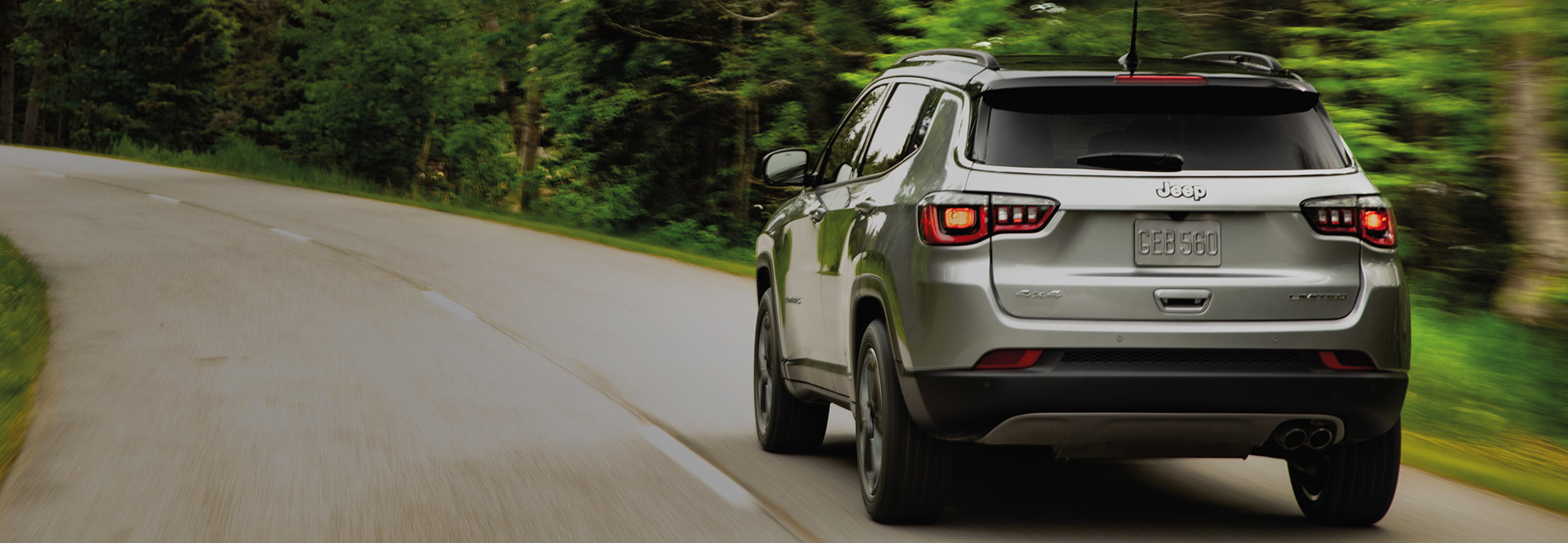 L’arrière d’un Jeep Compass de 2022 sur une route forestière.