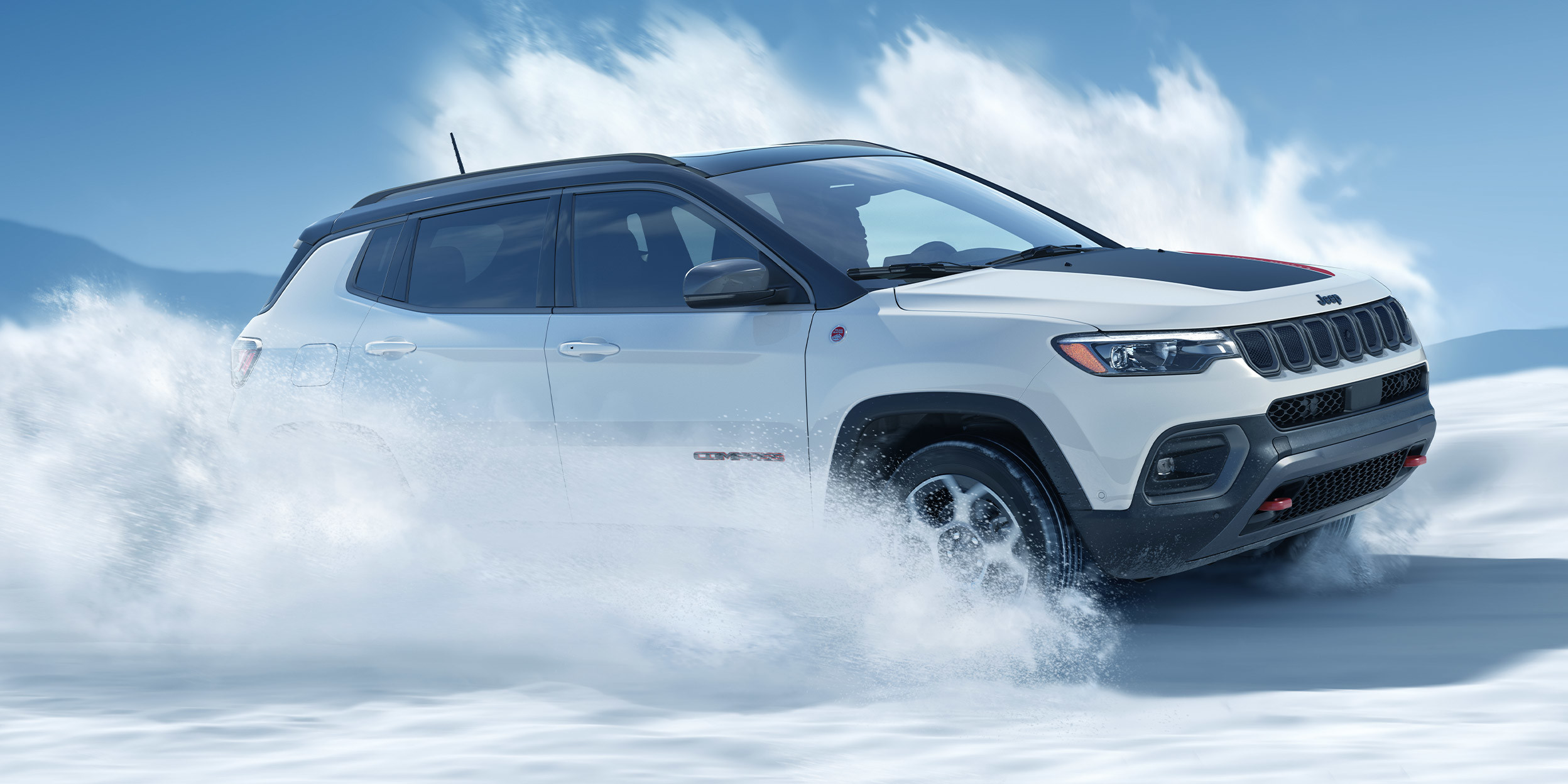 Compass Trailhawk blanc éclatant roulant dans la neige.
