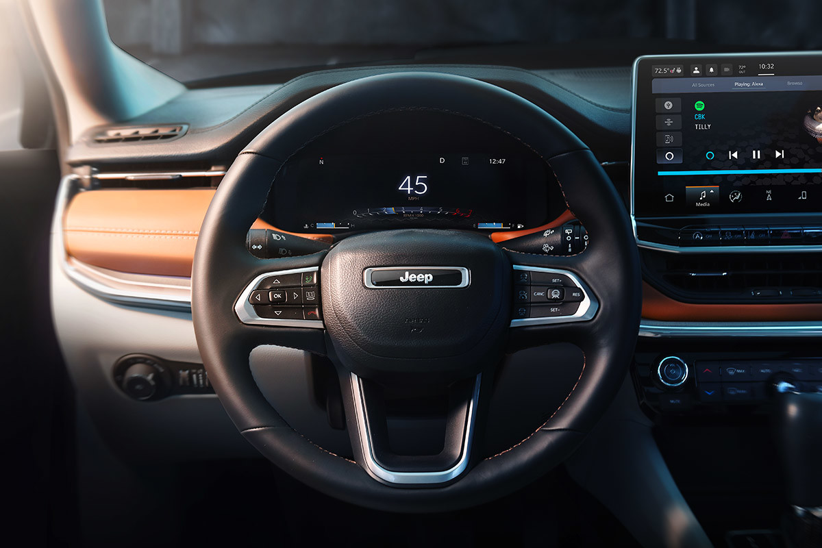 Gros plan sur le tableau de bord du Jeep Compass 2022 redessiné montrant le volant, le groupe d’instruments et l’écran tactile.