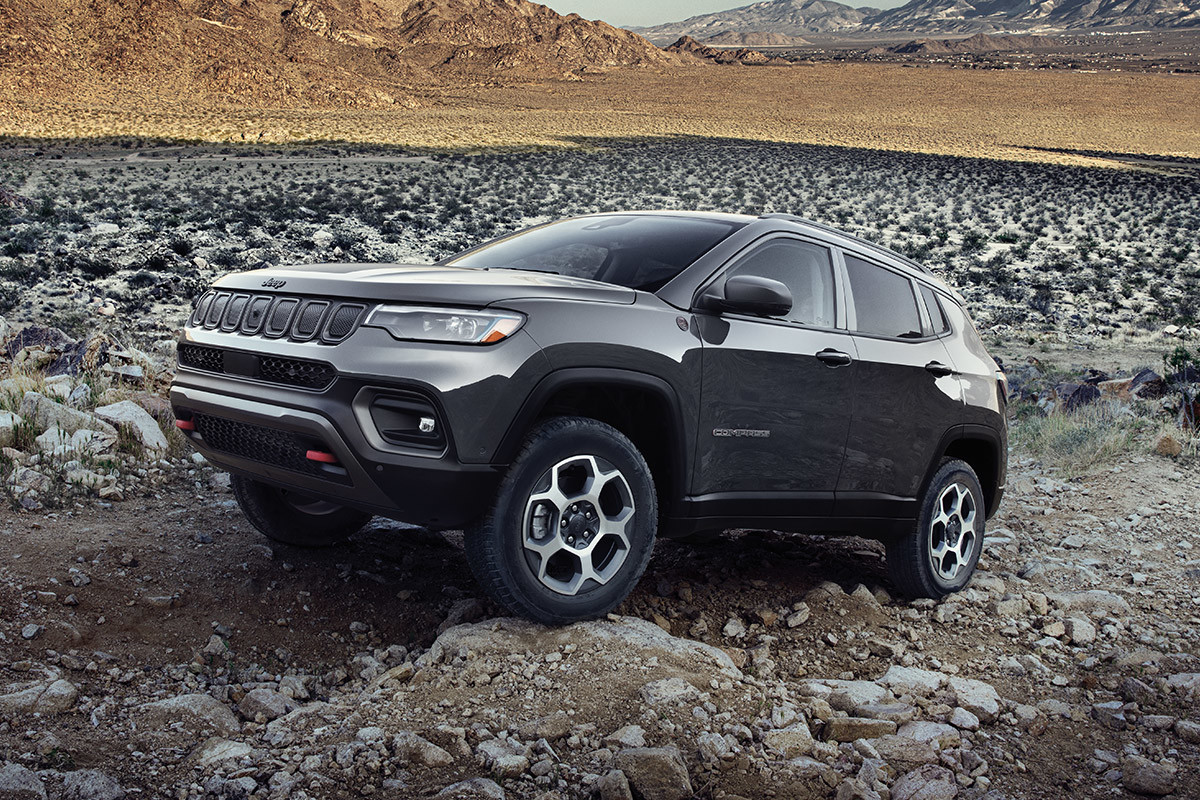 A grey 2022 Jeep Compass driving off road over rocks.