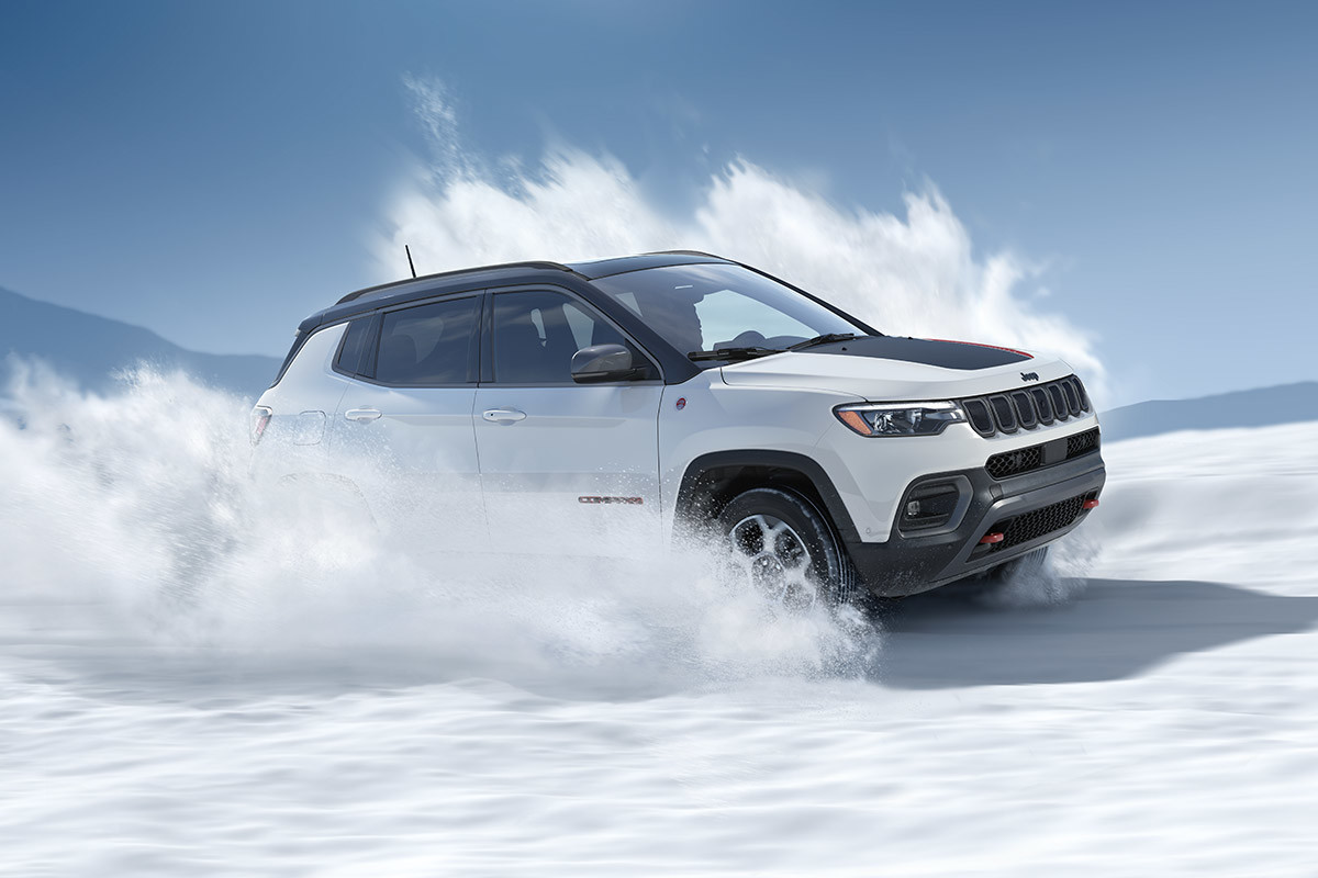 A white 2022 Jeep Compass driving off road through snow.