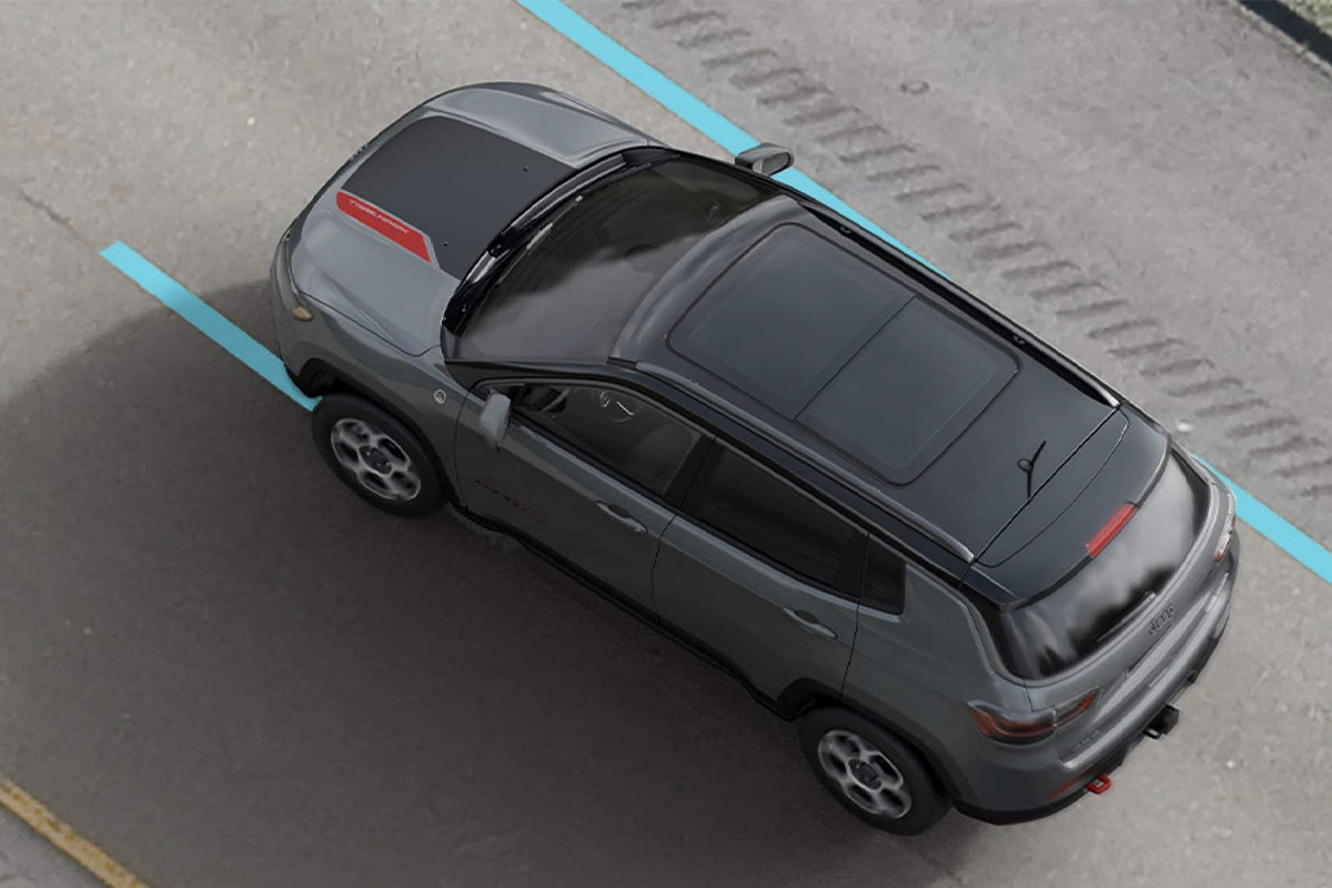 L'arrière d'un Jeep Compass argenté 2022 roulant sur une route forestière