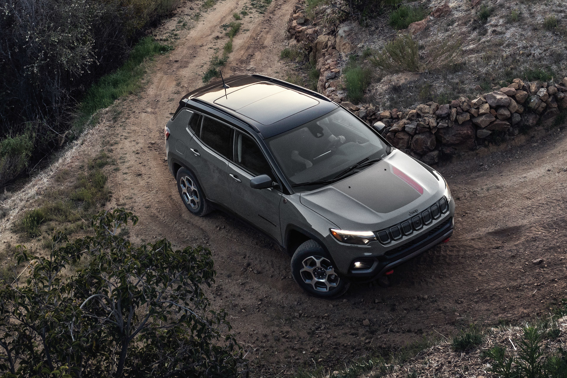 Une vue de haut en bas d'un Jeep Compass 2022 gris garé sur un chemin de terre