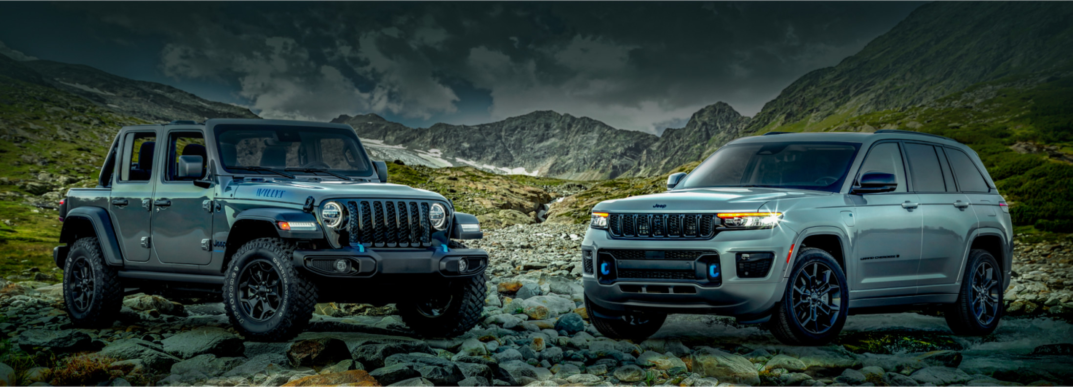 BIENVENUE DANS L’ÈRE ÉLECTRIQUE Vue de deux modèles de véhicules électriques Jeep 2023 stationnés sur un terrain rocheux.