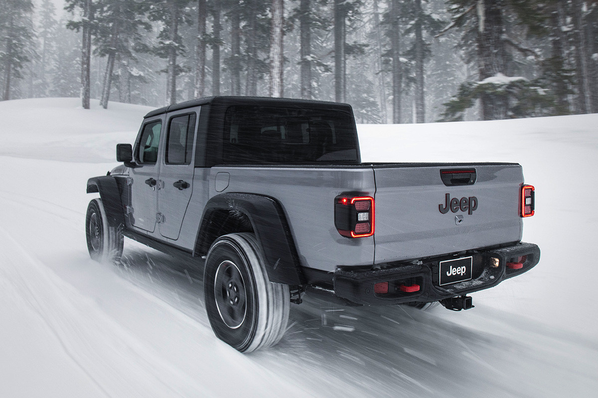 Rear view of the all-new 2020 Jeep Gladiator in grey driving through a snow-covered forest