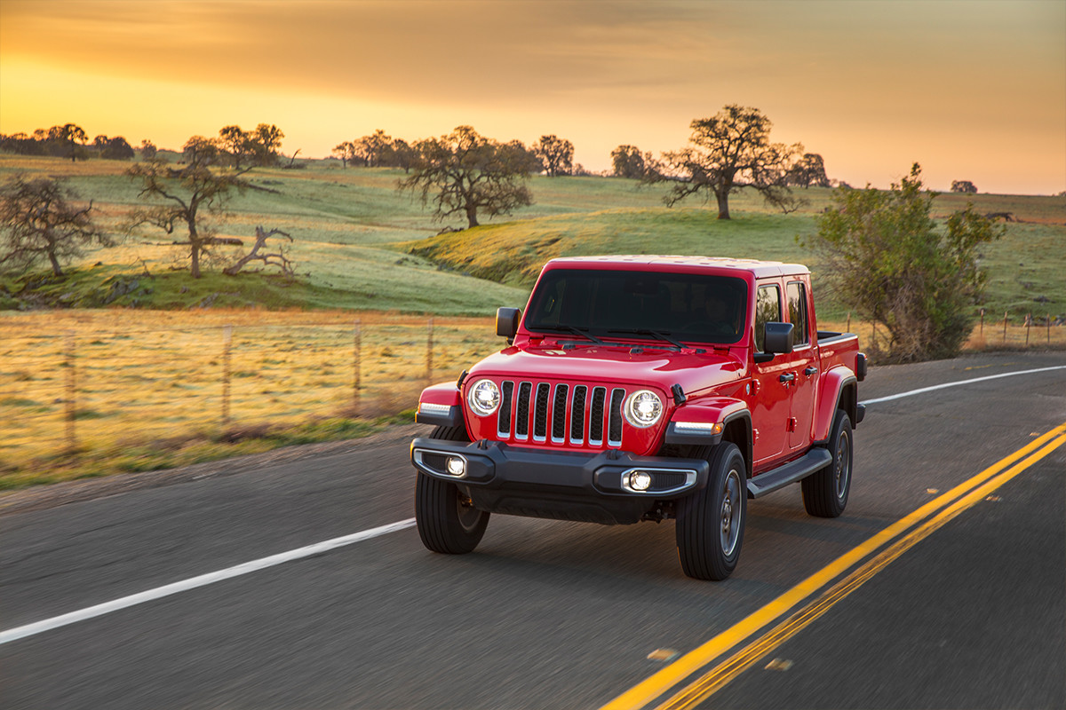 Vue avant du Jeep Wrangler 2020, illustré en rouge, roulant sur une route à travers les plaines