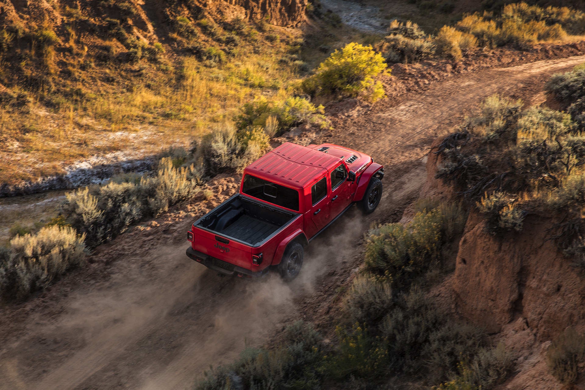 Plan en plongée de l’extérieur du Jeep Gladiator 2020 roulant dans le désert, illustré en rouge.