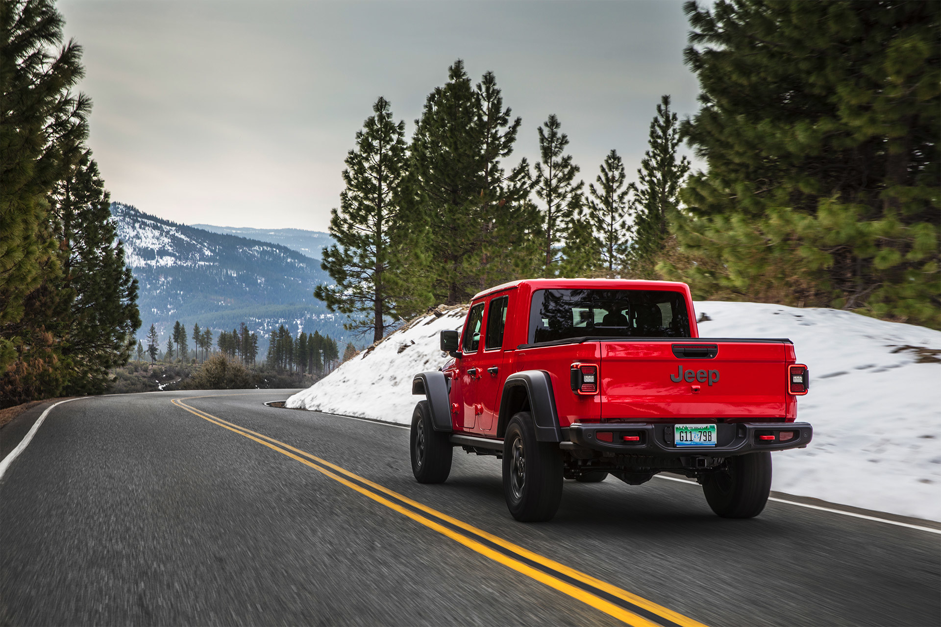 Rear view of the all-new 2020 Jeep Gladiator in red driving on a mountain road