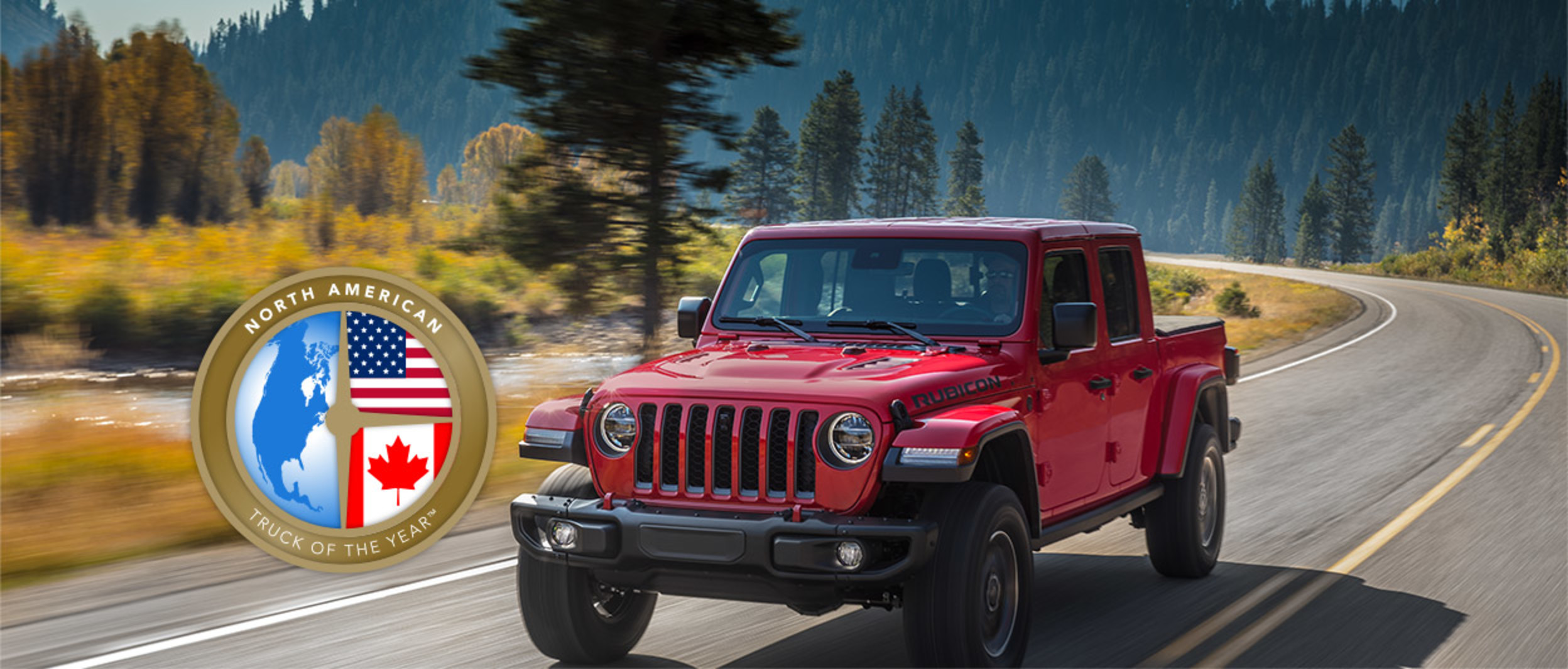 A red 2020 Jeep Wrangler being driven down the road with mountains in the background