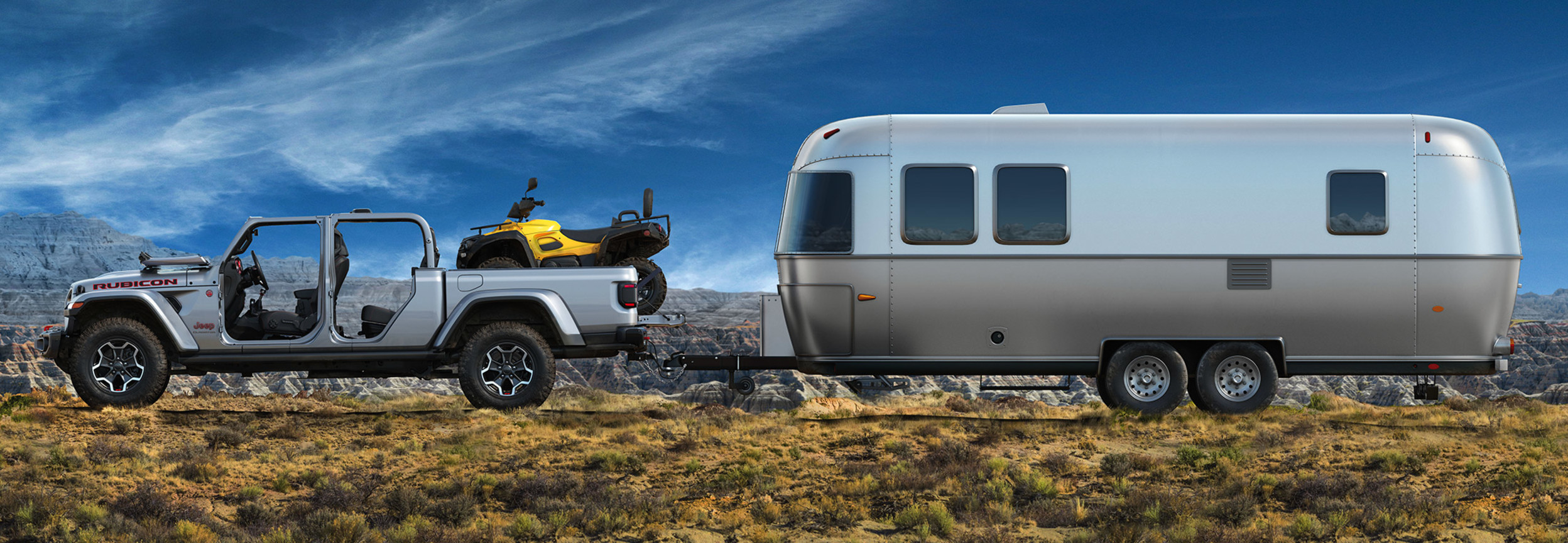 Side shot of Jeep Gladiator parked on off-road terrain with an ATV in the pickup bed and a trailer in tow.