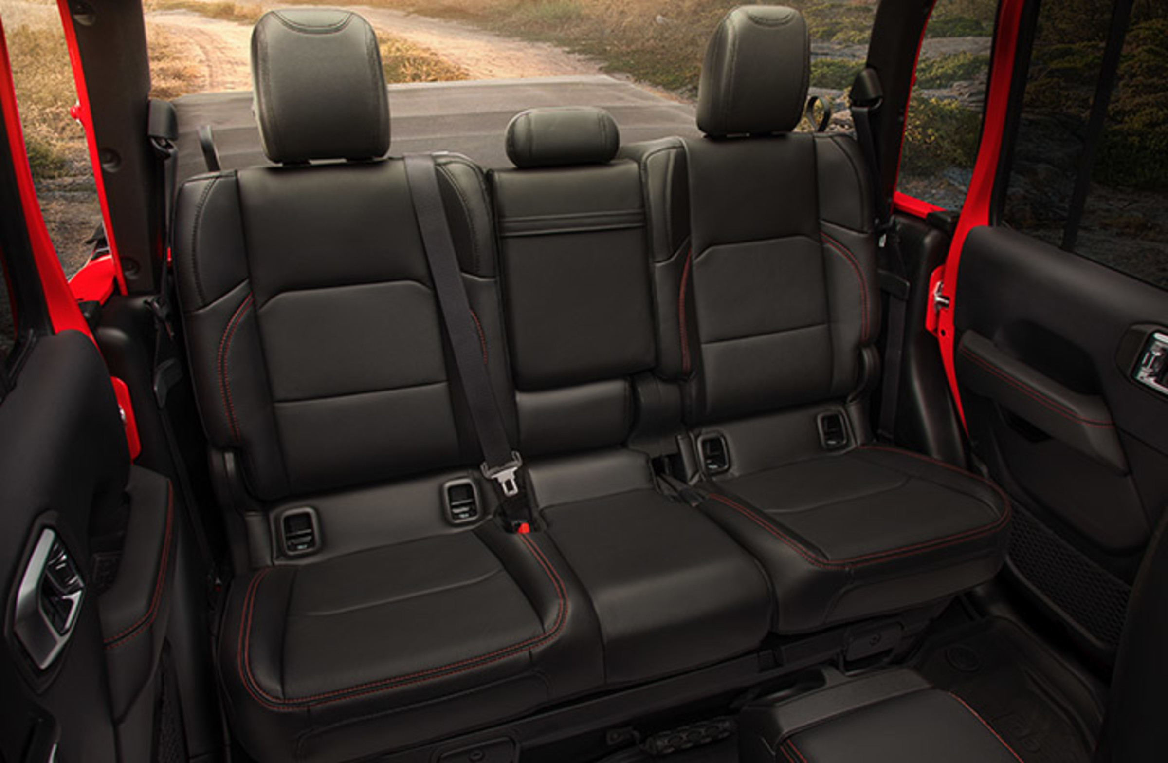 Gros plan des sièges arrière spacieux dans un Jeep Gladiator 2021 rouge pétard, le toit étant retiré.