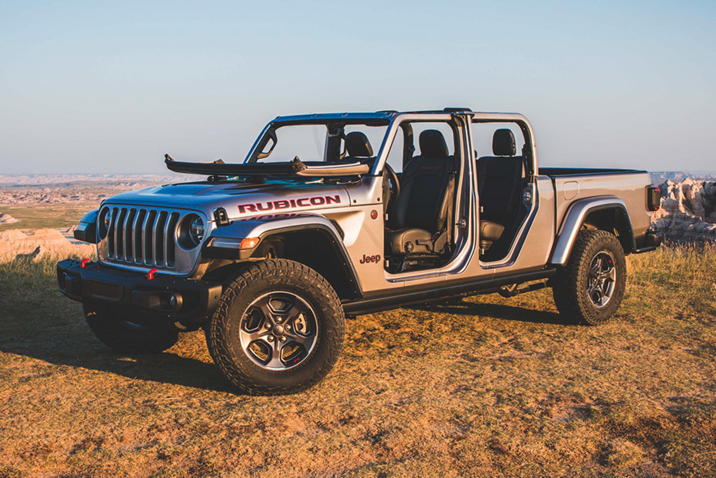 Vue en plongée d’un Jeep Gladiator 2021 gris acier argenté métallisé garé sur une route de terre.