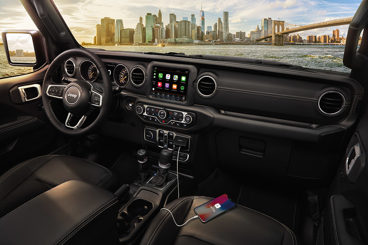 Plan intérieur d’un Jeep Gladiator présentant le volant, le système Uconnect et un téléphone portable branché au port USB.