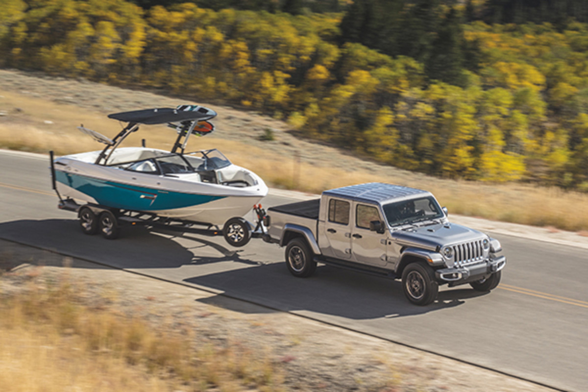 A grey 2022 Jeep Gladiator towing a boat on a highway.