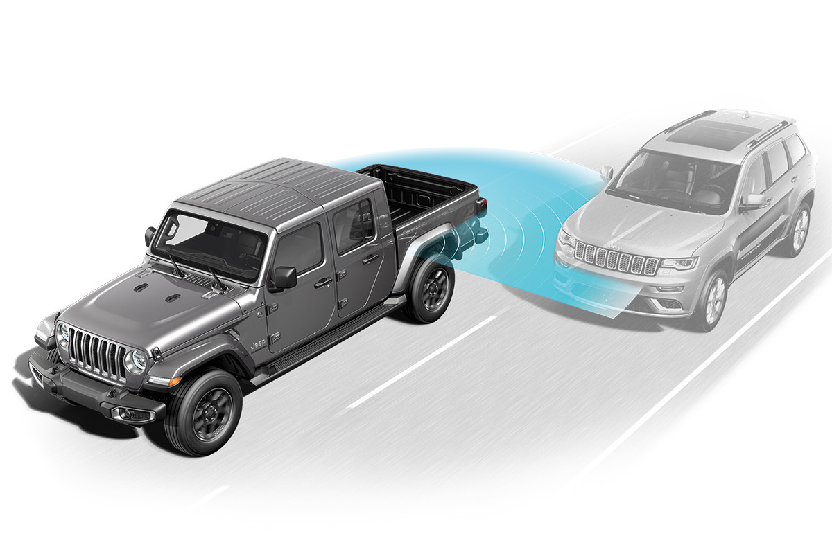 A 2022 Jeep Gladiator driving with a blue outline behind touching another car, showing off the blind spot monitoring.