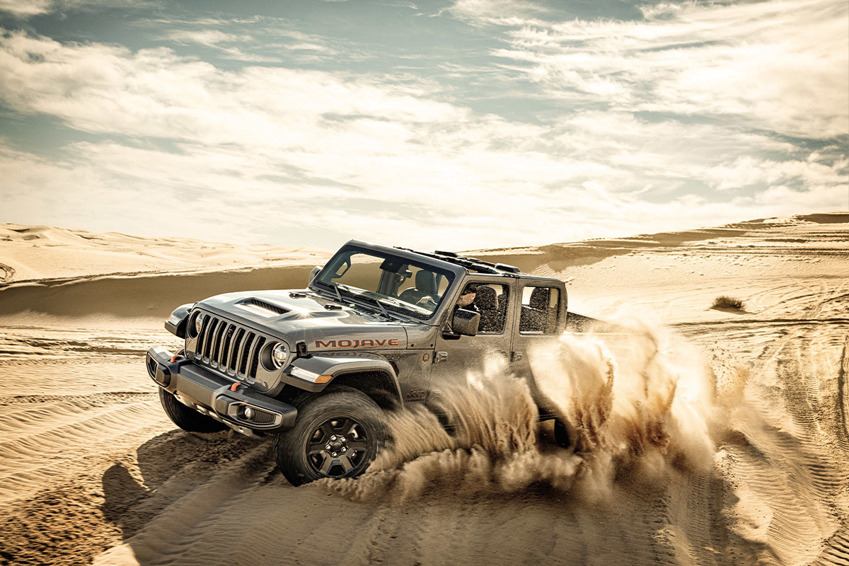 A grey 2022 Jeep Gladiator drifting through the sand.